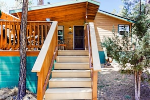 Une cabane en bois avec une véranda, un escalier et une pancarte indiquant «Bienvenue».