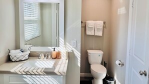 Un baño con tocador, inodoro y perchero para toallas.