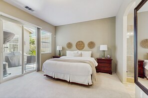 A bedroom with a large bed, a nightstand, a dresser, and a sliding glass door leading to an outdoor patio. - Desert Vibes, Festival Nights, and Poolside Delights! Close to Coachella (Indio)