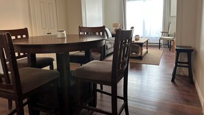 A dining area with a wooden table and chairs, a sofa, and a view of the outdoors through large windows. - Downtown Digs (St. John's)