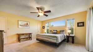 A bedroom with a bed, a ceiling fan, a window, and a nightstand.