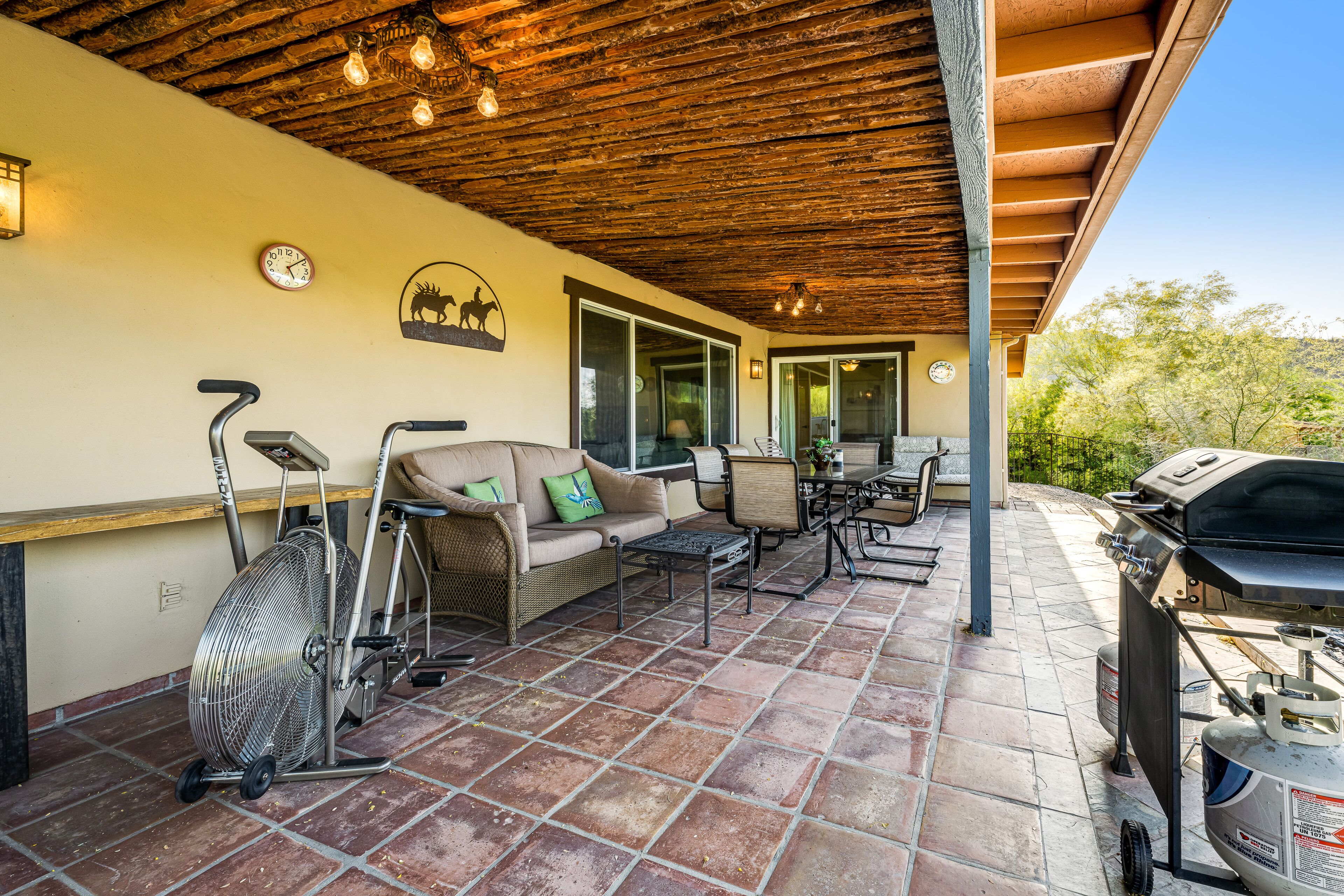 An outdoor patio with a ceiling fan, a sofa, a table, and a grill.