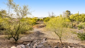 A desert landscape with a dirt path leading to a structure in the distance.