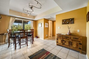 A dining area with a table and chairs, a wooden cabinet, and a view through a window. - Dog-friendly, Cave Creek home with covered patio, hot tub & mountain views (Cave Creek)