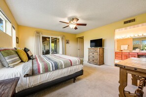 Quarto com cama, penteadeira, televisão e mesa de jantar.