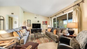 A living room with a sofa, armchairs, a coffee table, and a TV.