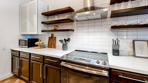 Eine moderne Küche mit weißen Schränken, Edelstahlgeräten und Holzregalen.