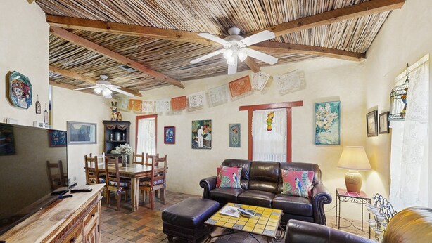 A living room with a television, leather sofa, and a dining area with chairs and a table. - Southwestern home in a great downtown Tucson location w/ furnished patio & yard (Tucson)