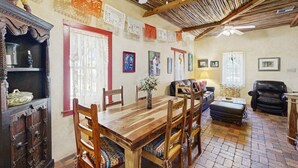 A dining area with a wooden table and chairs, a fireplace, and a ceiling fan. - Southwestern home in a great downtown Tucson location w/ furnished patio & yard (Tucson)
