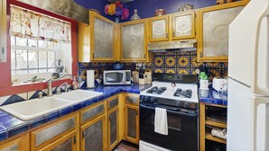 A kitchen with blue and yellow patterned tiles, wooden cabinets, a white sink, a black stove, and a microwave. - Southwestern home in a great downtown Tucson location w/ furnished patio & yard (Tucson)