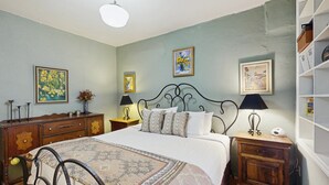A bedroom with a bed, bedside tables, a dresser, and wall art. - Southwestern home in a great downtown Tucson location w/ furnished patio & yard (Tucson)