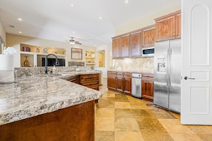 A spacious kitchen with granite countertops, wooden cabinets, and stainless steel appliances. - Relaxing home & casita with private pool, pool spa, grill & outdoor fireplaces (Palm Desert)