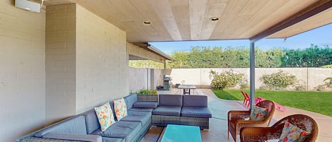 An outdoor patio with a sectional sofa, wicker chairs, and a table.