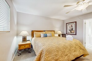 A bedroom with a bed, nightstands, a ceiling fan, and a door. - Large home w/ a full kitchen, furnished patio, & private, outdoor pool (Phoenix)