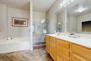 Un baño moderno con bañera, ducha, un espejo grande y armarios de madera.