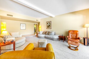 Ein Wohnzimmer mit einem Ecksofa, einem Schaukelstuhl und einem kleinen Beistelltisch.