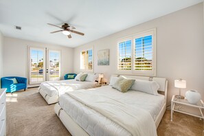 A bedroom with two beds, a ceiling fan, and a view of the outdoors through large windows. - Dazzling retreat w/ a pool, grill, firepit, game room, & W/D - snowbird friendly (Indio)