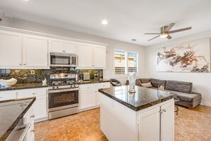 Een moderne keuken met witte kastjes, granieten aanrechtbladen, roestvrijstalen apparatuur en een centraal eiland.