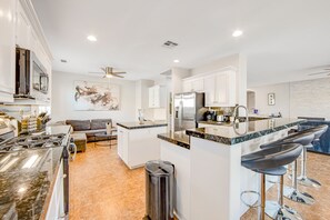 A modern kitchen with white cabinets, a stainless steel refrigerator, and a granite countertop. - Dazzling retreat w/ a pool, grill, firepit, game room, & W/D - snowbird friendly (Indio)