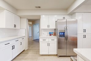 A modern kitchen with white cabinetry, stainless steel appliances, and a clean, minimalist design.
