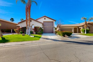 A residential street with houses, well-maintained lawns, and palm trees. - Luxe and spacious retreat with a pool, pool spa, firepit, grill, game room, & AC (Indio)
