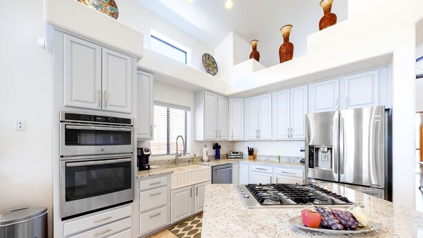 Una cocina moderna con gabinetes blancos, electrodomésticos de acero inoxidable y encimera de granito.