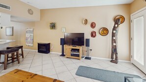 Una sala de estar con televisor, muebles de madera y objetos decorativos en la pared.