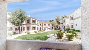 A courtyard with buildings, a small lawn, and a table with a plant. - Inviting Condo w/ a Shared, Heated Pool, Hot Tub, Fitness Room & Sauna (Scottsdale)