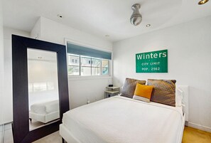 A bedroom with a bed, a mirror, a window, and a sign indicating 'Winters City Limit POP: 2562'. - Updated modern condo w/ shared pool & mountain views - near downtown (Palm Springs)