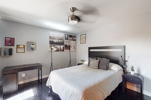 Ein modernes Schlafzimmer mit einem großen Bett, einem Nachttisch, einem Schreibtisch und einem Deckenventilator.