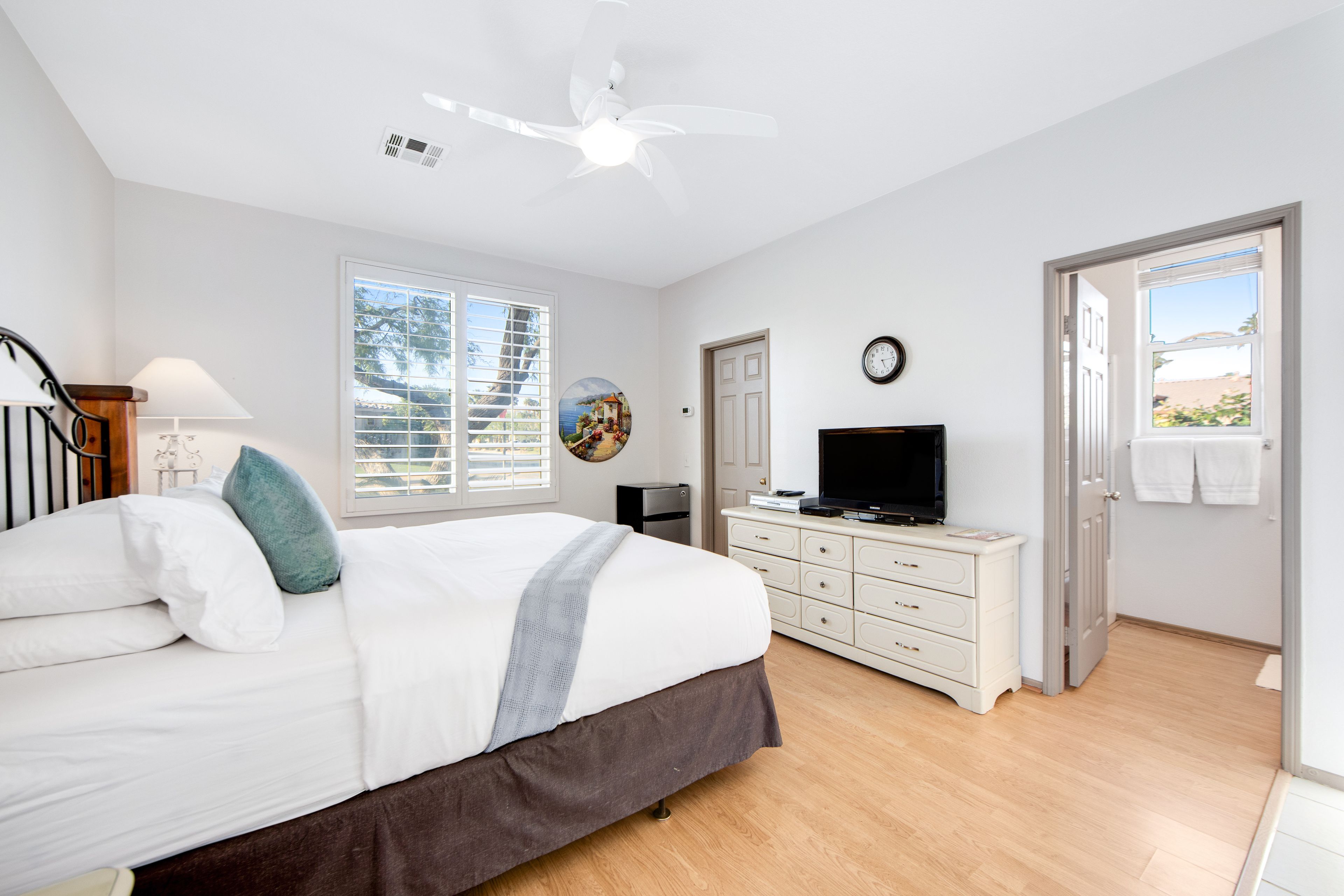A bedroom with a bed, a TV, a dresser, and a ceiling fan.