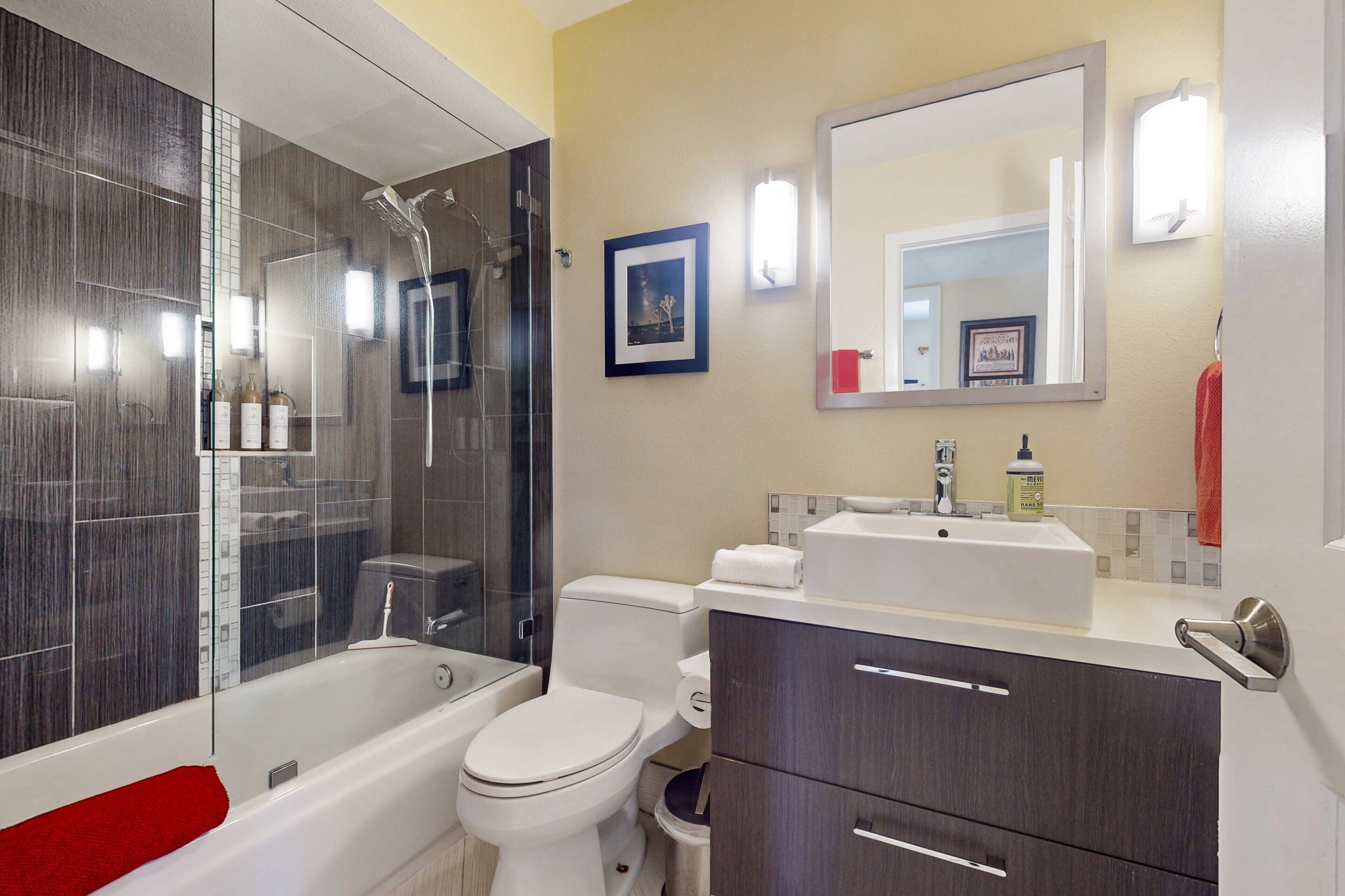 Une salle de bain moderne avec une douche à parois de verre, des toilettes blanches et un meuble-lavabo avec un évier et un miroir.