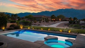 Ein Swimmingpool mit Blick auf Berge und einen Sonnenuntergang.
