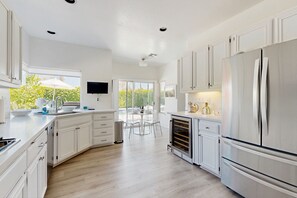 Una cocina moderna con armarios blancos, un refrigerador grande y un horno empotrado.