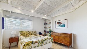 A bedroom with a bed, bedside table, dresser, and a bookshelf. - Dog-friendly mountain view condo with pool, grill, open layout, AC, & internet (Palm Desert)