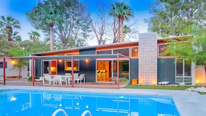 A modern house with a swimming pool, outdoor seating, and large windows. - Elegant, mid-century Alexander butterfly home w/ pool & gas grill (Palm Springs)