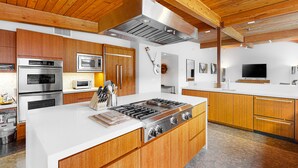 A modern kitchen with wooden cabinets, stainless steel appliances, and a large island. - Elegant, mid-century Alexander butterfly home w/ pool & gas grill (Palm Springs)