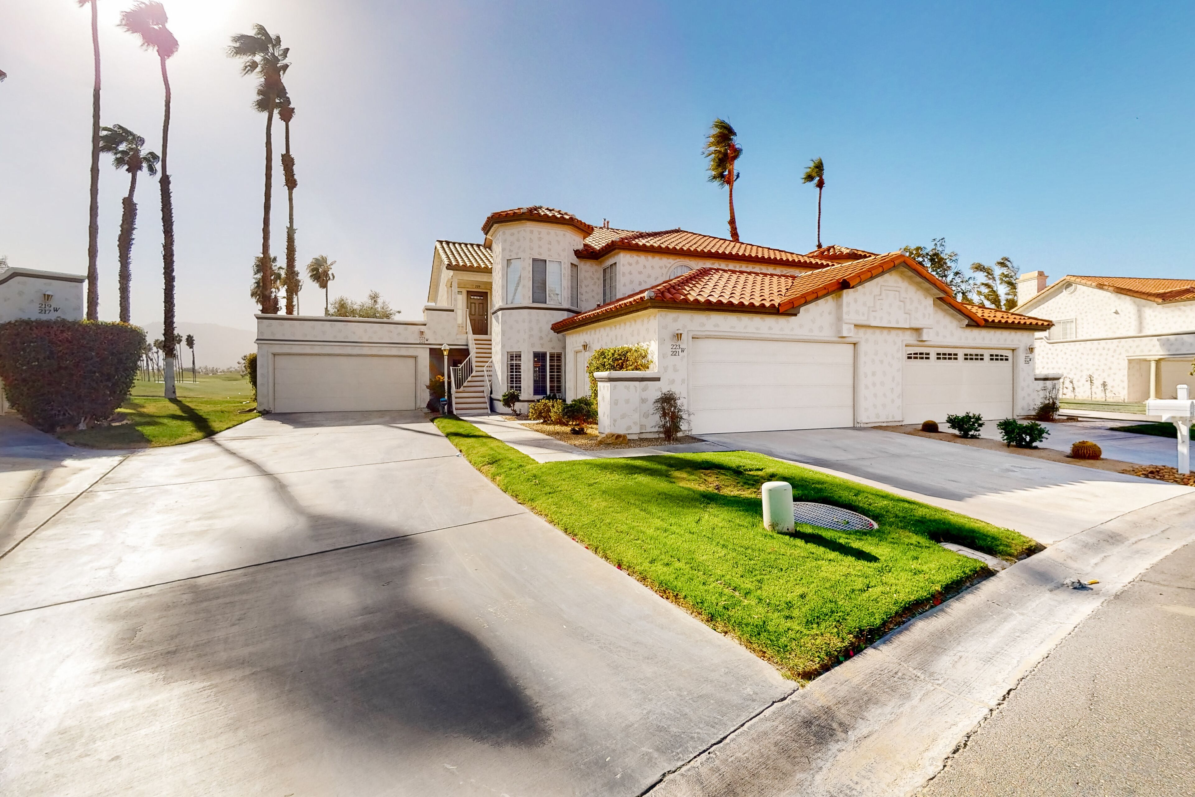 A residential house with a curved roof, a well-maintained lawn, and a driveway leading to the garage.