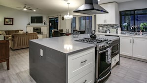 Cozinha moderna com ilha central, forno embutido e eletrodomésticos de aço inoxidável.