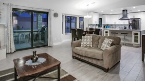Uma sala de estar moderna com sofá, mesa de centro e área de jantar com cadeiras.