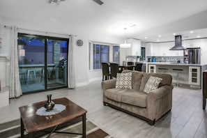 A modern living room with a sofa, coffee table, and a dining area with chairs. - Dog-friendly desert gem w/private pool, putting green, firepit, & more (Palm Springs)