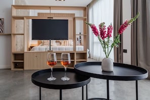 A modern hotel room with a flat-screen TV, a sofa, a coffee table with two glasses of wine, and a vase with flowers. - Estudio Moderno & Amplio en Palermo (Buenos Aires)