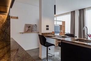 A modern kitchen with a marble countertop, a bar stool, a wine glass, and a pendant light. - Estudio Moderno & Amplio en Palermo (Buenos Aires)
