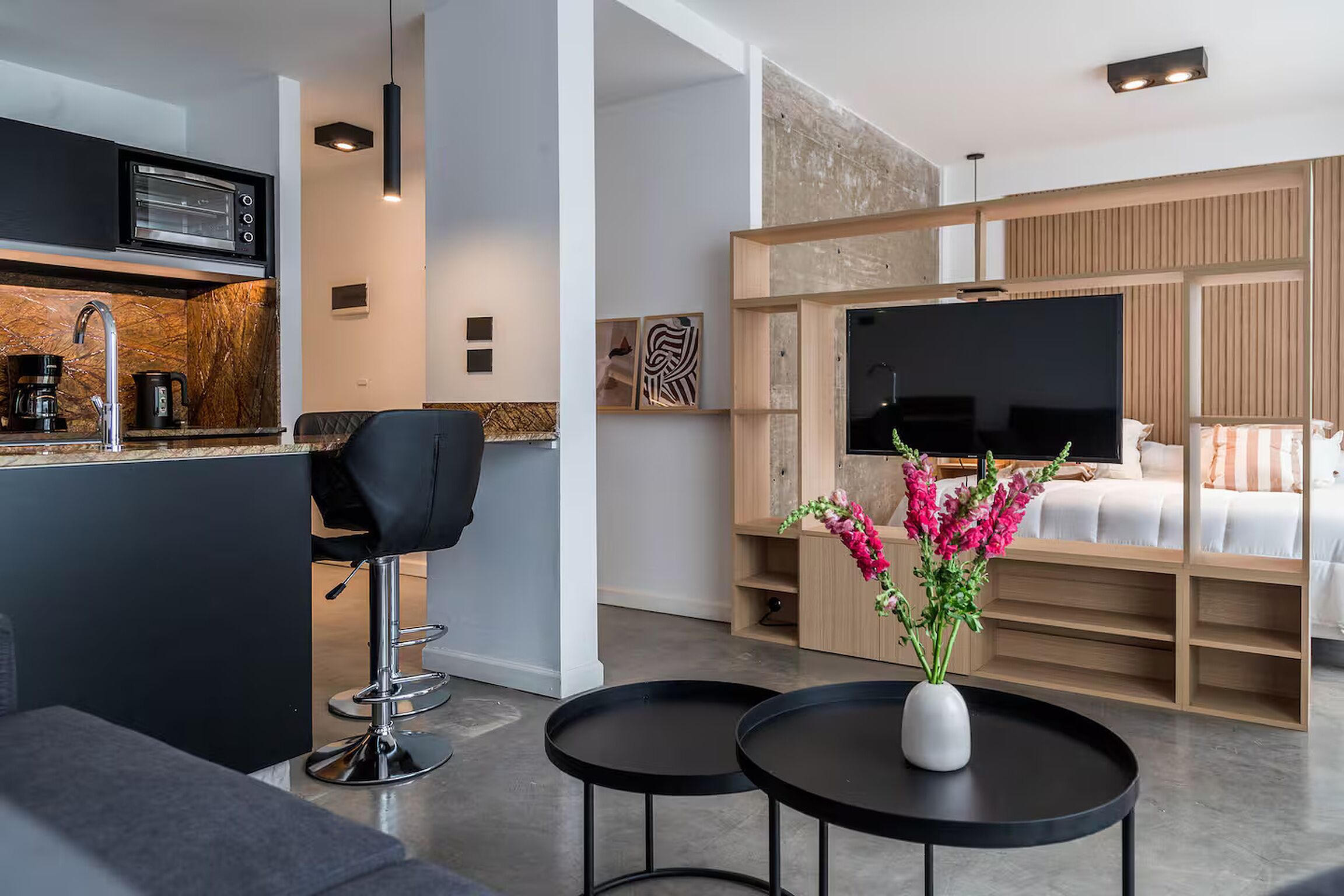 Een moderne woonkamer met een bank, een koffieapparaat, een televisie en een bloevas.