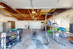 Eine Garage mit Holzbalkendecke, einer Hantelständer, Kurzhanteln und einer Gewichtbank.