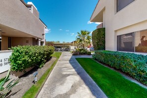 A residential street with houses, a sidewalk, and a clear blue sky.