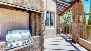 An outdoor grill area with stone walls and a pergola.
