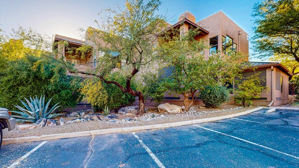A modern building with a parking lot and landscaped garden.