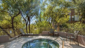 A swimming pool with a metal ladder, surrounded by trees and outdoor seating.