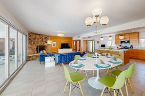 A modern living room with a stone wall, a blue sofa, and a dining area with green chairs and a white table. - Classic, mid-century modern home w/ mtn views, private pool and spa - dogs OK (Palm Springs)